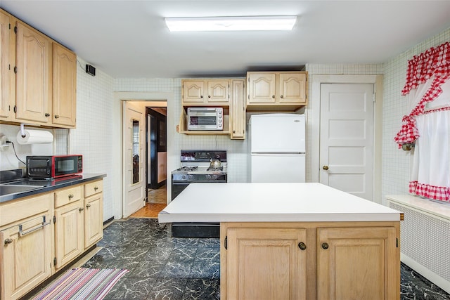 kitchen featuring light brown cabinets, freestanding refrigerator, gas stove, radiator, and wallpapered walls