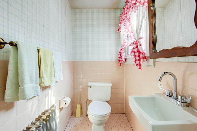 bathroom with radiator heating unit, a sink, tile walls, toilet, and tile patterned floors