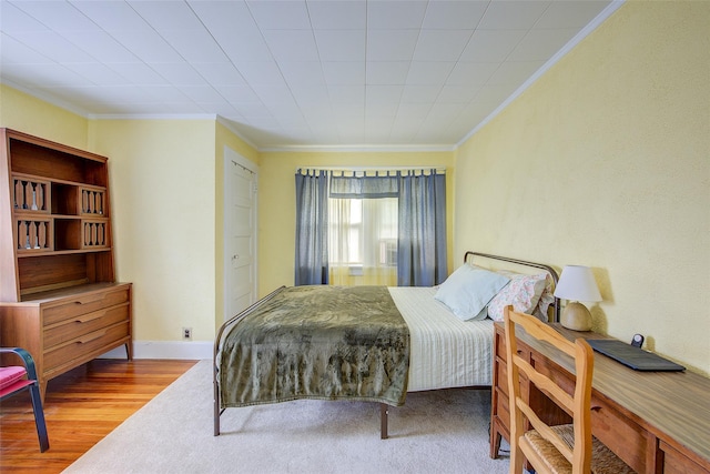 bedroom featuring crown molding, baseboards, and wood finished floors