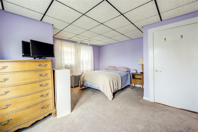 bedroom with light colored carpet, radiator, a paneled ceiling, and baseboards