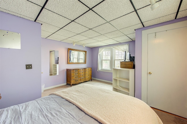 bedroom with carpet flooring, baseboards, and a drop ceiling