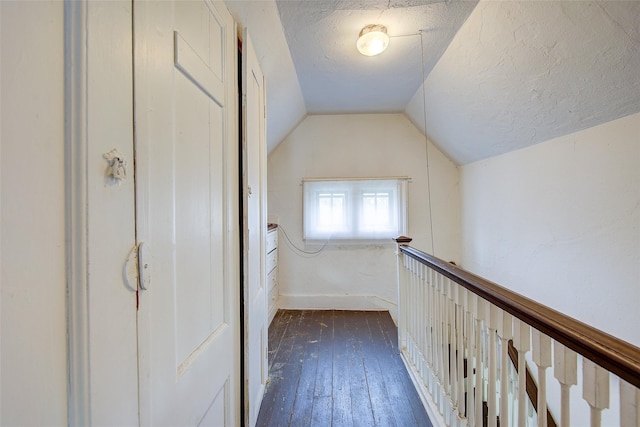 corridor with a textured ceiling, dark wood-type flooring, and lofted ceiling