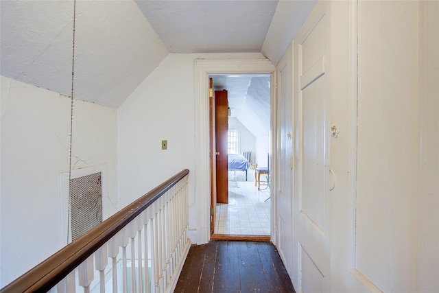 hallway with vaulted ceiling, visible vents, and dark wood-style flooring