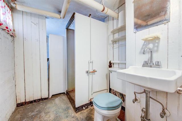 half bathroom with toilet, concrete flooring, and a sink