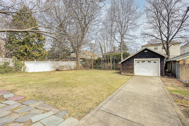 view of yard featuring a garage, an outdoor structure, a fenced backyard, and driveway