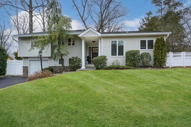 view of front of home featuring stone siding, aphalt driveway, a front yard, and fence