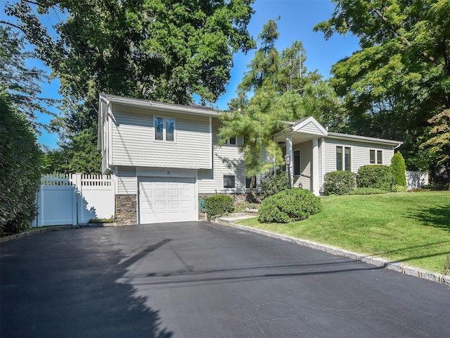 view of front facade featuring stone siding, aphalt driveway, a gate, fence, and a front yard