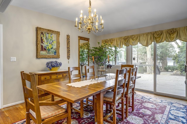 dining area featuring light wood-type flooring, baseboards, a chandelier, and lofted ceiling