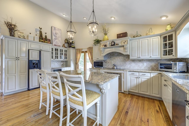 kitchen featuring light wood-type flooring, a kitchen island, paneled built in fridge, and a kitchen breakfast bar