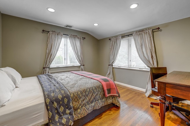 bedroom with hardwood / wood-style floors, multiple windows, visible vents, and baseboards