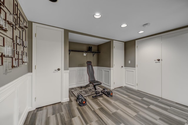 exercise room featuring wainscoting, wood finished floors, and recessed lighting