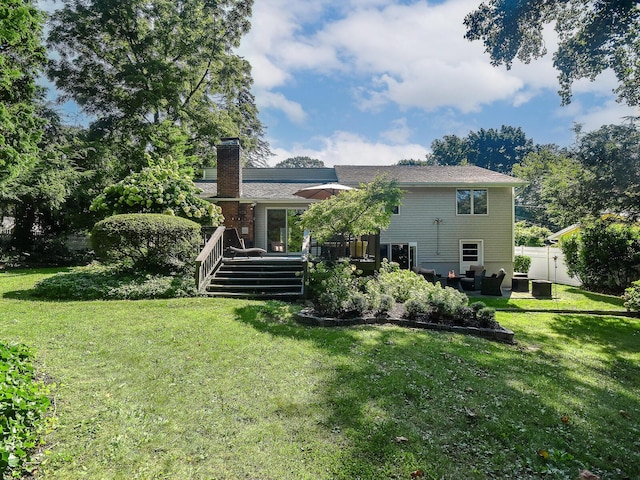 back of property with a chimney, fence, a deck, and a yard