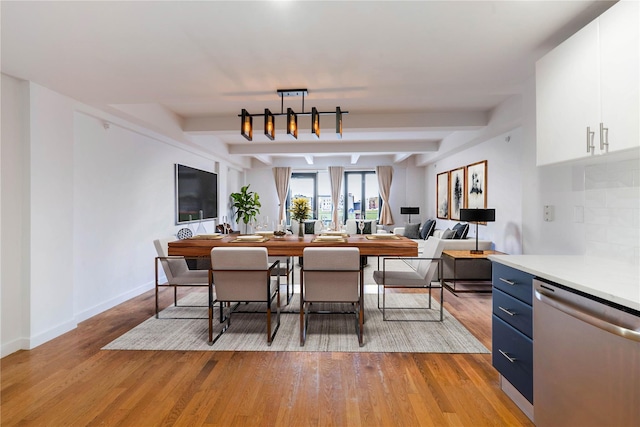 dining area featuring beam ceiling, light wood-style flooring, and baseboards