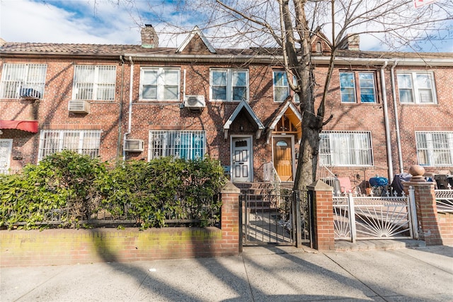 view of property with brick siding, a fenced front yard, a chimney, and a gate