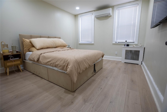 bedroom with a wall unit AC, light wood-style flooring, recessed lighting, baseboards, and radiator heating unit