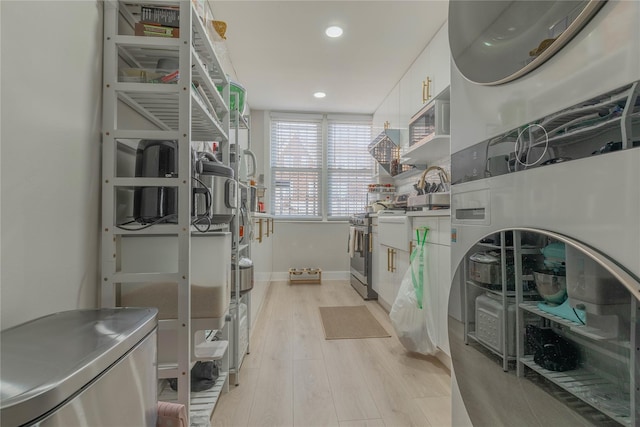 interior space with light wood finished floors, baseboards, stacked washer / drying machine, and recessed lighting