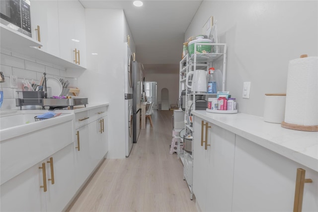 kitchen featuring white cabinetry, light wood finished floors, tasteful backsplash, and stainless steel microwave