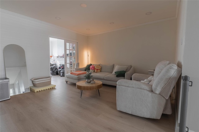 living room featuring light wood-style floors, arched walkways, and crown molding