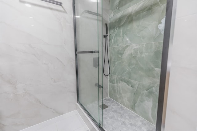 bathroom with a marble finish shower and tile patterned floors