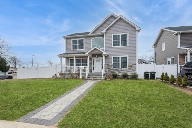 view of front of house with a porch, stone siding, fence, and a front lawn