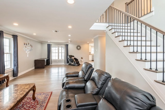 living room with baseboards, light wood-style flooring, visible vents, and crown molding