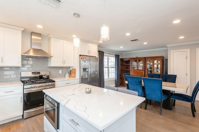 kitchen featuring visible vents, wall chimney range hood, light wood finished floors, and appliances with stainless steel finishes