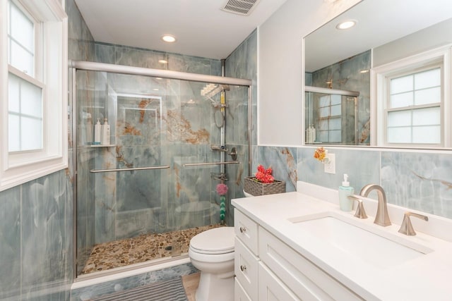 full bathroom featuring toilet, a shower stall, visible vents, and tile walls