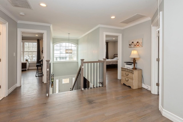 corridor with visible vents, crown molding, an upstairs landing, and wood finished floors