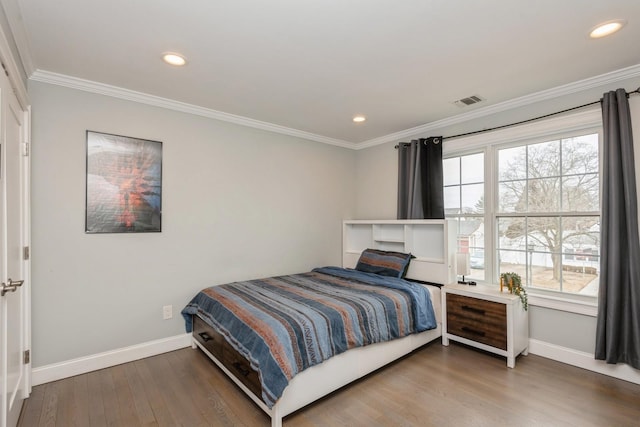 bedroom with visible vents, crown molding, baseboards, and wood finished floors