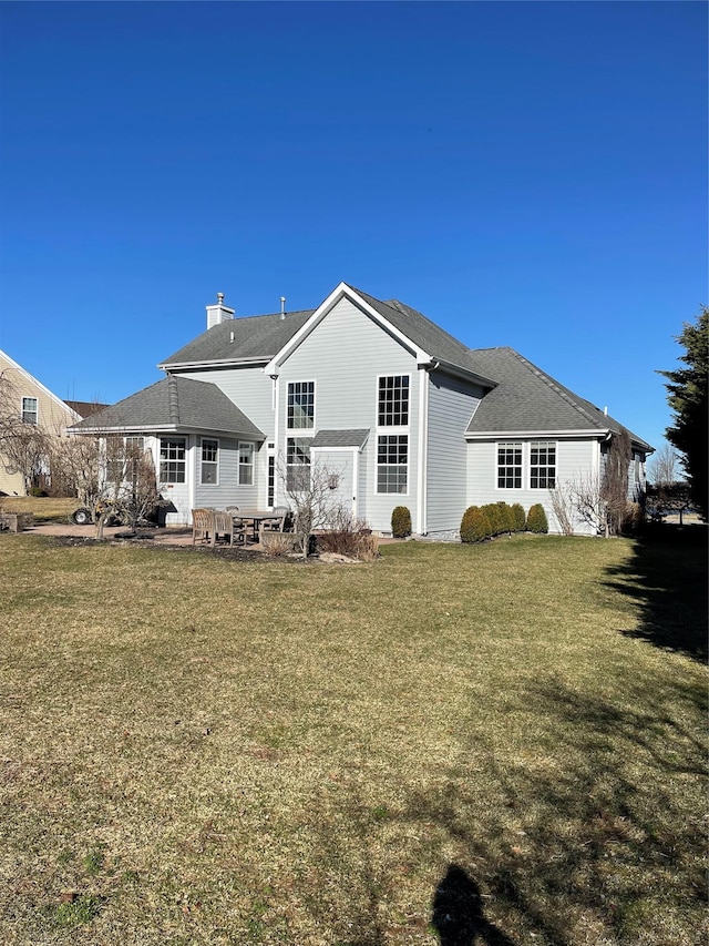 rear view of property with a chimney and a lawn