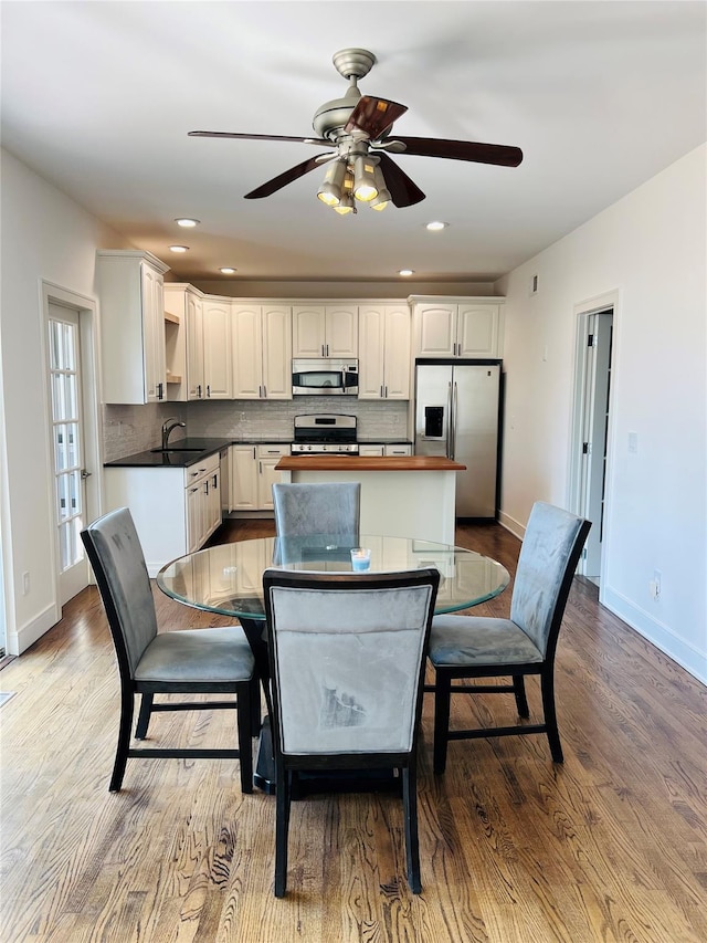 kitchen featuring tasteful backsplash, stainless steel appliances, a sink, and wood finished floors