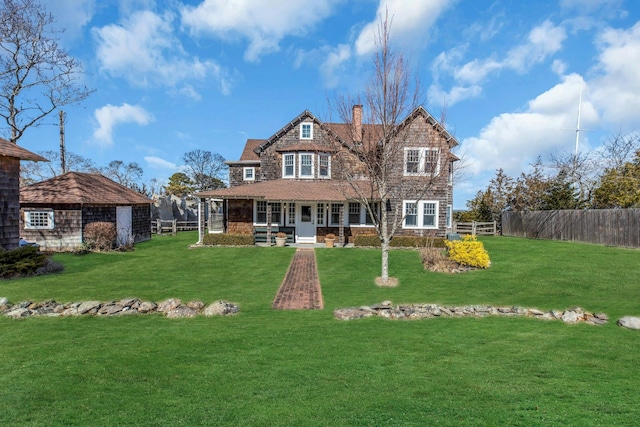 rear view of property with a porch, a yard, fence, and a chimney