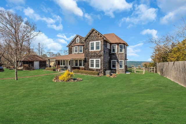 rear view of property featuring fence private yard, a yard, and a shingled roof