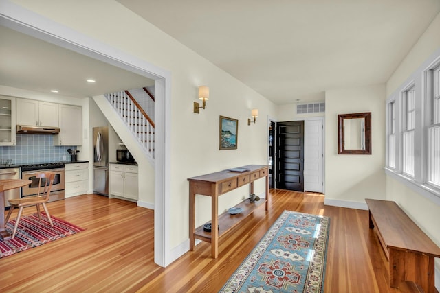 interior space with visible vents, light wood-style flooring, recessed lighting, baseboards, and stairs