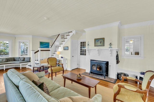 living area with stairs, a wood stove, wood finished floors, and ornamental molding