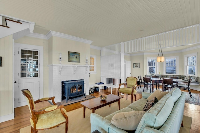 living area featuring crown molding, a wood stove, and wood finished floors