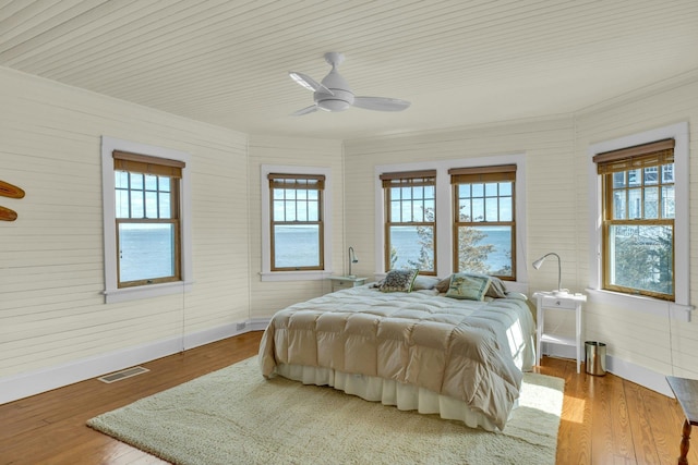 bedroom featuring ceiling fan, wood finished floors, visible vents, and baseboards