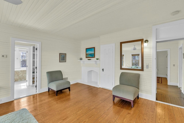 sitting room with a fireplace, baseboards, and wood finished floors