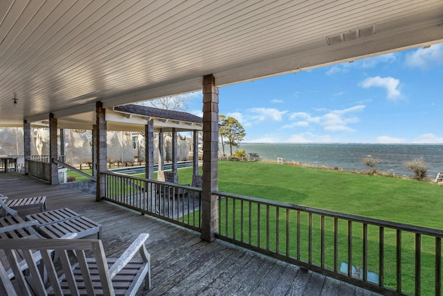 wooden deck with a water view and a lawn