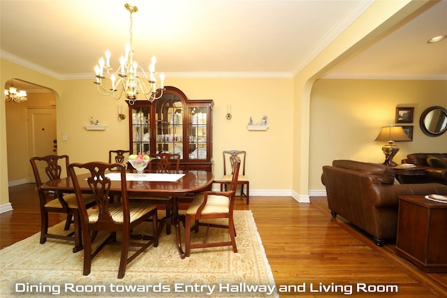 dining room featuring ornamental molding, arched walkways, an inviting chandelier, and wood finished floors