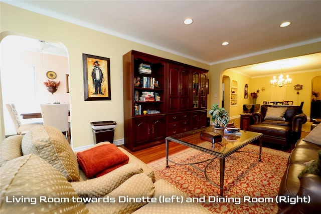 living room with arched walkways, crown molding, recessed lighting, wood finished floors, and a chandelier