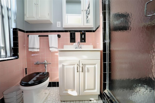 bathroom with toilet, tile patterned floors, vanity, a shower stall, and tile walls