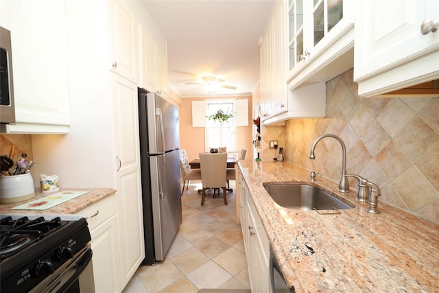 kitchen with decorative backsplash, a ceiling fan, glass insert cabinets, appliances with stainless steel finishes, and a sink