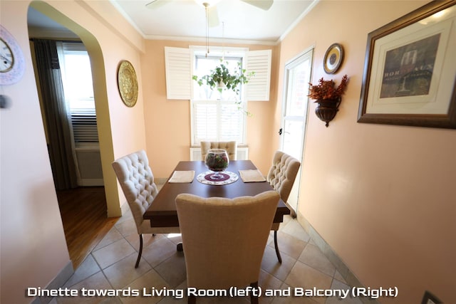 dining space with arched walkways, baseboards, tile patterned floors, and crown molding