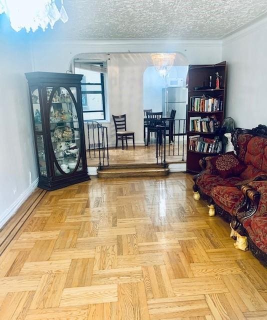 sitting room with ornamental molding, a notable chandelier, a textured ceiling, and baseboards