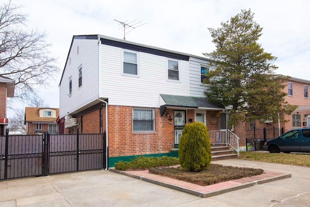 view of front of house featuring a gate, fence, and brick siding