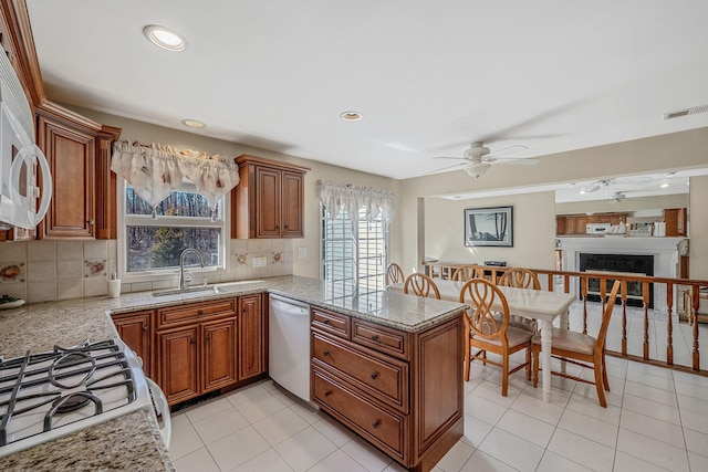 kitchen with a fireplace, backsplash, brown cabinetry, white appliances, and a peninsula