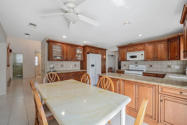 kitchen featuring brown cabinets, white appliances, visible vents, and light tile patterned floors