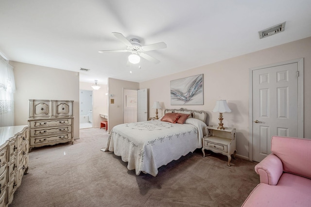 bedroom with light carpet, a ceiling fan, visible vents, and ensuite bathroom