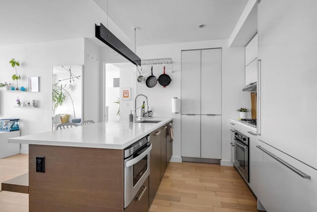 kitchen featuring modern cabinets, appliances with stainless steel finishes, a peninsula, light countertops, and a sink